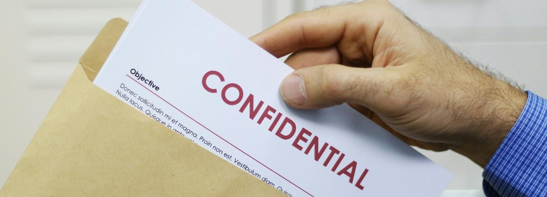 man pulling a paper out of an envelope that says confidential