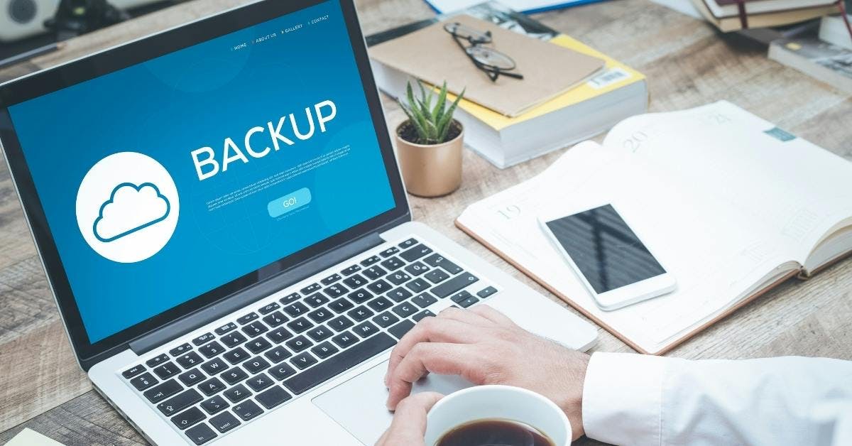 someone on their laptop and the screen says backup with a cloud icon